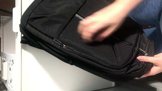 一个女人看了一眼黑色背包。用拉链检查背包视频素材模板下载
