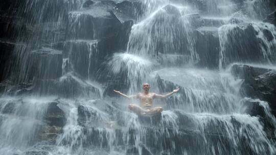 男子坐在瀑布下摆瑜伽姿势