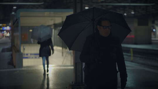 雨夜城市灯光下，两个人在火车站雨伞下握手