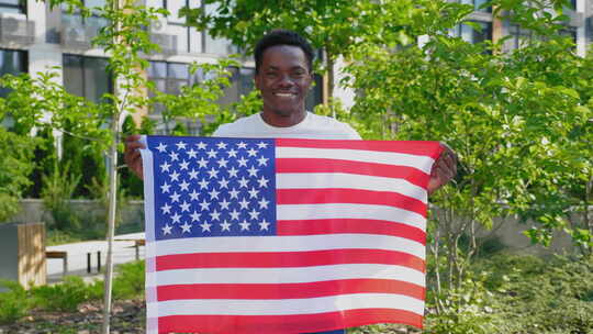 肖像微笑的非裔美国人拿着美国国旗和相机视频素材模板下载