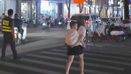 夜色街道，镜头跟随，妇女背小孩过斑马线