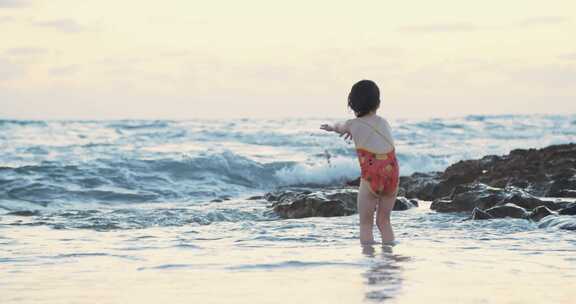 年轻女孩站在海水中捡起沙子