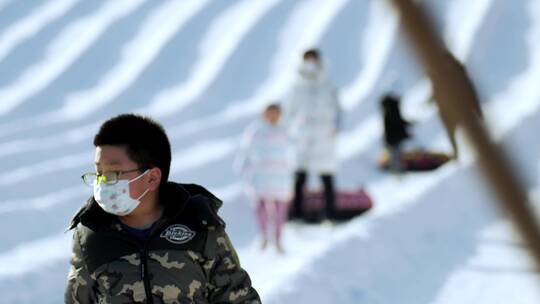 4K升格实拍冬季在冰雪乐园玩雪圈滑梯的游人