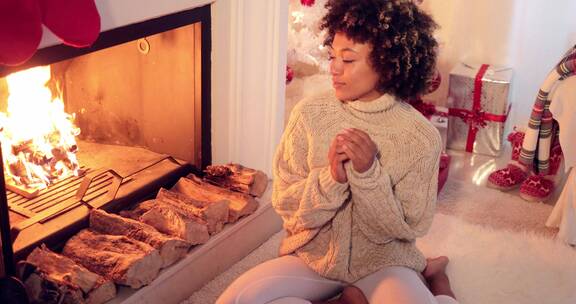 圣诞节坐在壁炉前烤火的女子