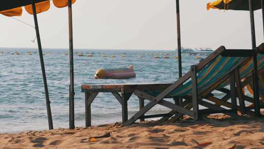 泰国芭堤雅沙滩上带伞的木制日光浴床视频素材模板下载