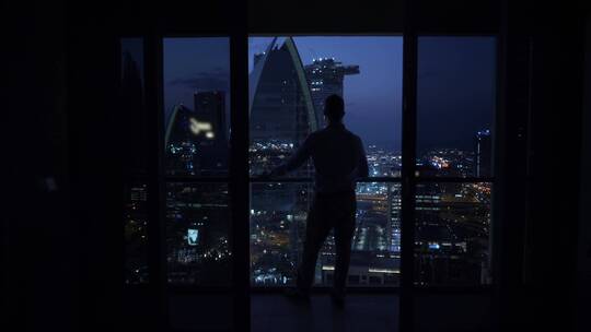 男人站在迪拜摩天大楼的阳台看夜景