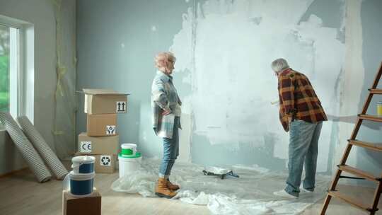 老人用油漆滚筒粉刷墙壁