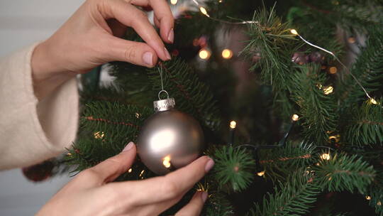 女人手在圣诞树上挂银球的特写镜头