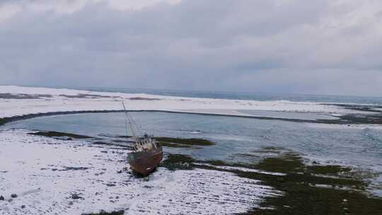 雪地海滩上一艘搁浅船只的无人机镜头