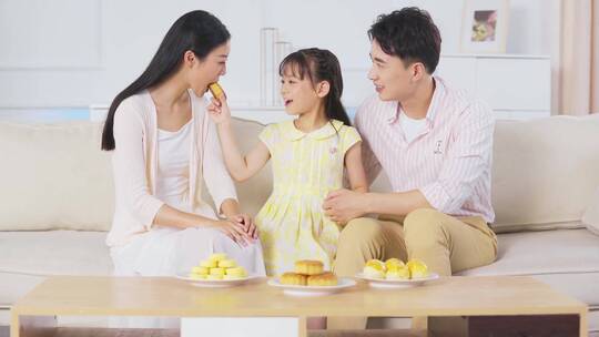 中秋节一家三口坐在沙发吃月饼