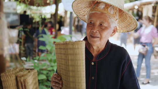 一位穿着当地服装的传统泰国编织垫店的老年