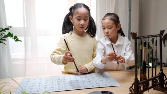 两个用字帖练习毛笔字的东方女孩