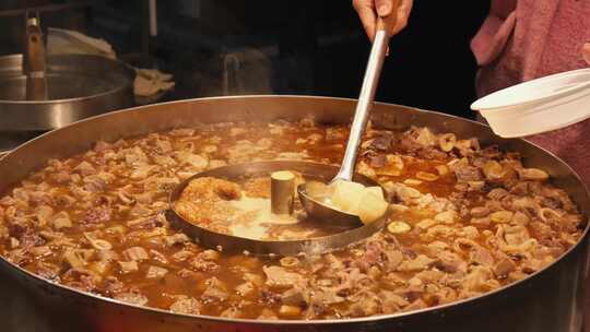 街头夜市用大勺搅拌大锅美食的场景