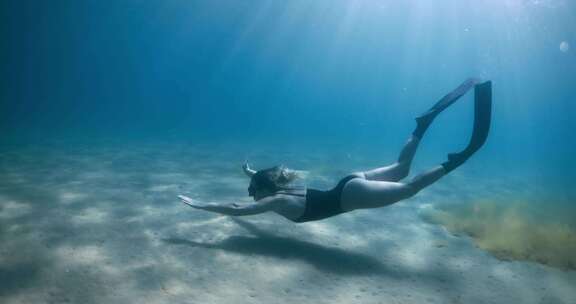 女子自由潜水员在蓝海水下游泳女子在水下用