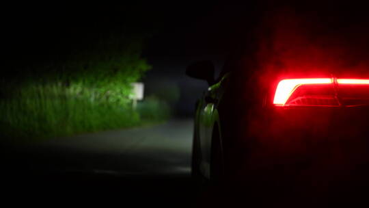 停在夜晚小道上的抛锚汽车开着后灯