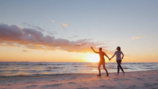 海滩上玩风筝的年轻夫妇
