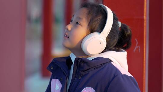 冬天阳光下坐在公园带耳机欣赏音乐的女孩