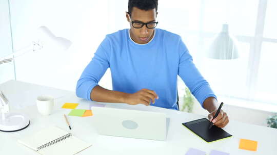非裔美国创意设计师在笔记本电脑上使用平板