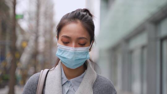 城市女青年戴口罩走在街头疫情期间