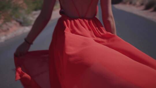 女人穿着红色太阳裙走在公路上