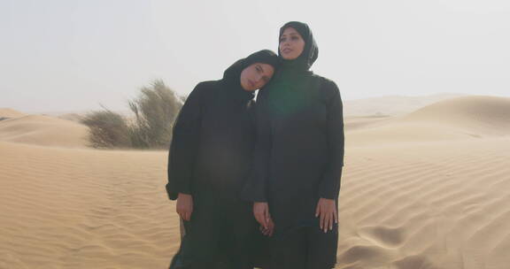 两个穿着黑色衣服的女人站在沙漠里拥抱