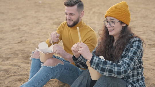 在海滩上吃食物的情侣