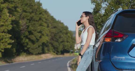 年轻沮丧的女人打手机，靠在车上，警告信号开着