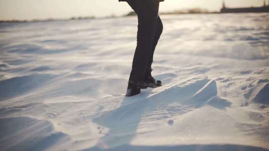 日落时分行走在雪地上的女性脚部特写