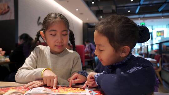 在餐厅翻阅菜单点餐的两个亚洲女孩视频素材模板下载