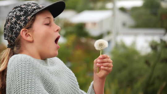 女孩吹着蒲公英泡芙球许下愿望，这样种子就