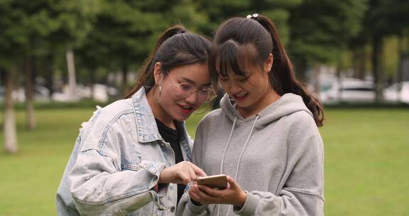 两位女大学生在校园看手机网购学习开心交谈