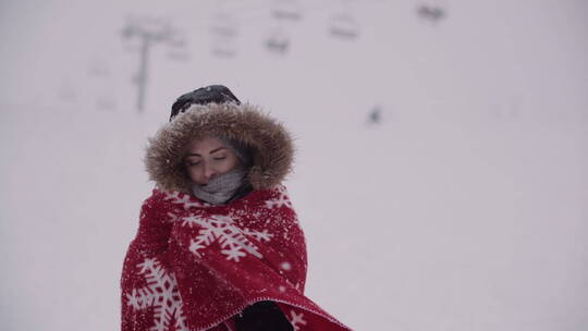 在雪中裹着红色毯子的女人