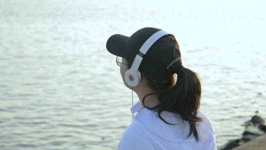 女孩在江边戴着耳机听歌4k视频素材