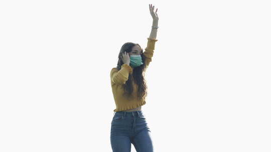技术，新冠病毒-戴着面具跳舞的女孩在电话里听音乐