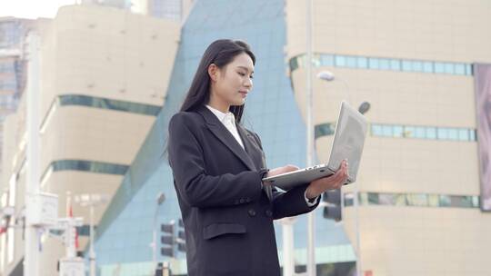 城市街道中使用电脑办公的青年女性