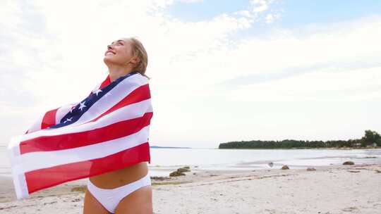 海滩上插着美国国旗的快乐女人视频素材模板下载