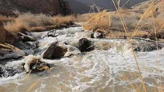 山间溪流湍急流淌且部分结冰的景象