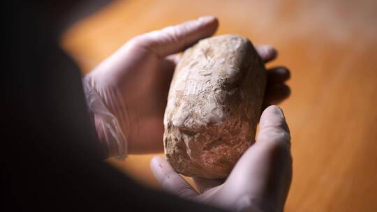 考古发掘人员手捧文物翻来覆去观察研究