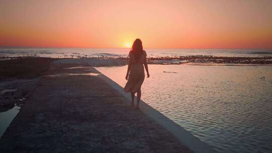 夕阳海边女人在岸边走路