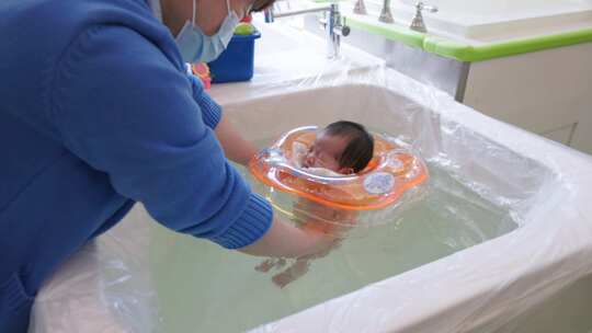 新生儿小孩宝宝在教练帮助下游泳