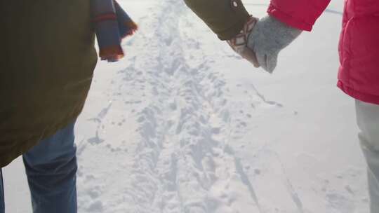 一对夫妇在雪地外散步时牵着手