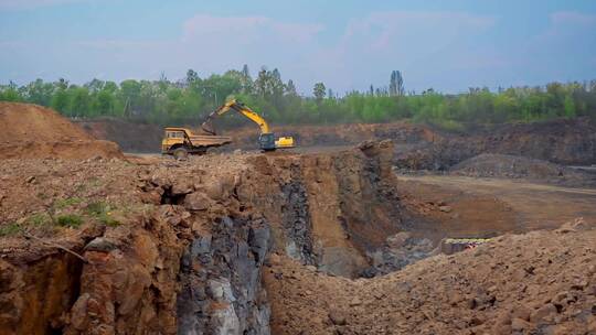 矿山上挖掘机在往卡车上装在沙土碎石