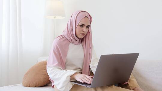 戴着粉色头巾的女人操作电脑视频素材模板下载