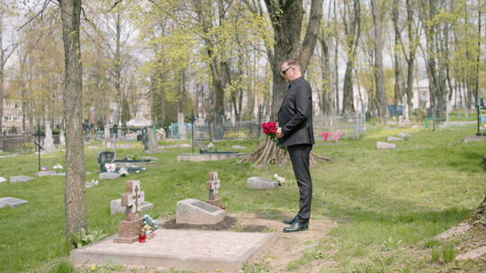 男人拿着红玫瑰站在坟墓前祭拜亲朋视频素材模板下载