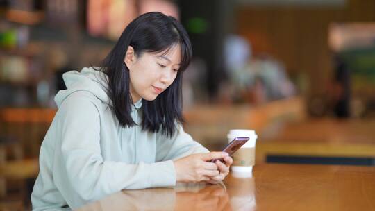 年轻女子在咖啡店使用智能手机通讯