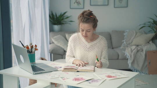 女人在笔记本电脑前翻阅笔记本的特写镜头视频素材模板下载