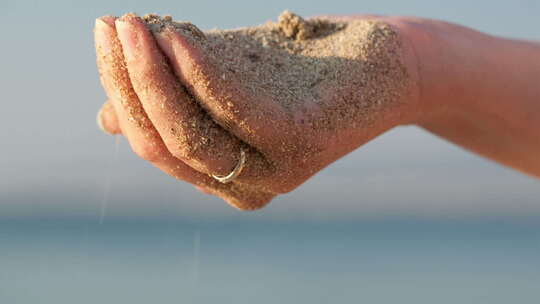 沙粒从手心坠落手捧沙沙子滑落洒落沙滩玩沙