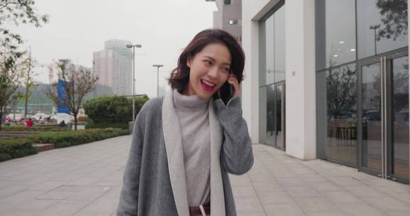快乐中国女青年职场白领走在街上手机打电话