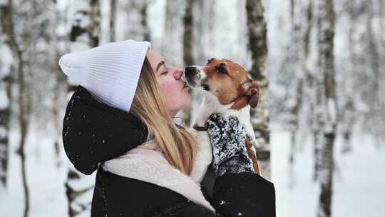 一个女孩在冬季森林里亲吻一只杰克梗犬视频素材模板下载