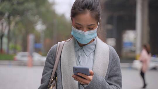 城市里戴口罩看手机的女青年